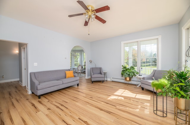 living room featuring ceiling fan, light hardwood / wood-style floors, a baseboard heating unit, and a wealth of natural light