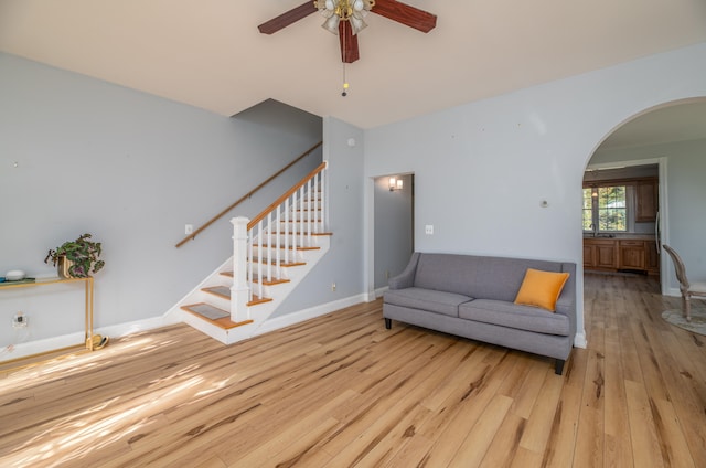 living room with light wood-type flooring, ceiling fan, and sink