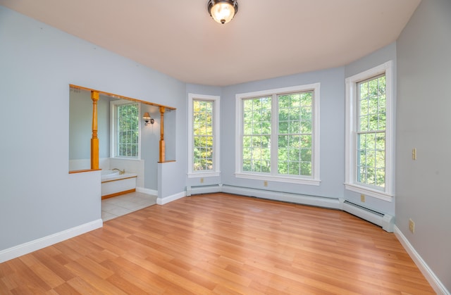 empty room featuring a baseboard radiator, light hardwood / wood-style flooring, and plenty of natural light