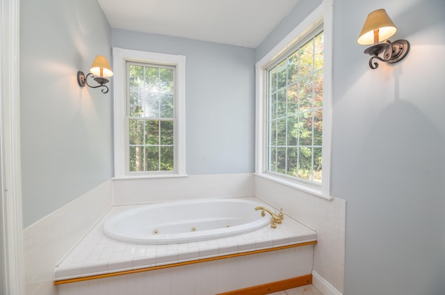 bathroom featuring tiled bath and a wealth of natural light