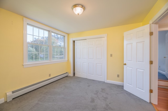 unfurnished bedroom with light carpet, a baseboard heating unit, and a closet