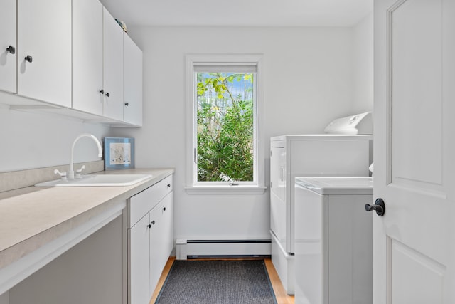 laundry area with washing machine and dryer, a healthy amount of sunlight, cabinets, and a baseboard radiator