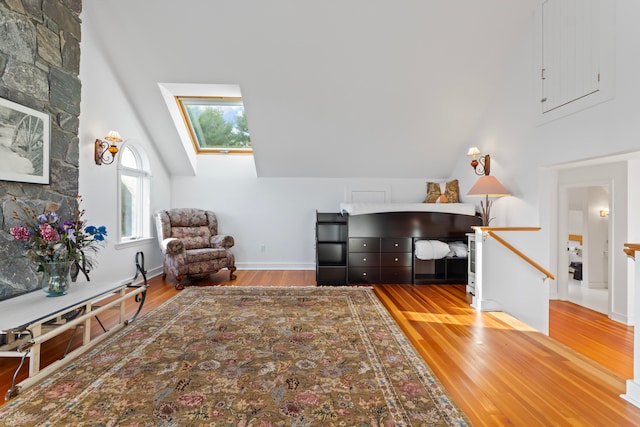 living area with wood-type flooring, a skylight, and high vaulted ceiling