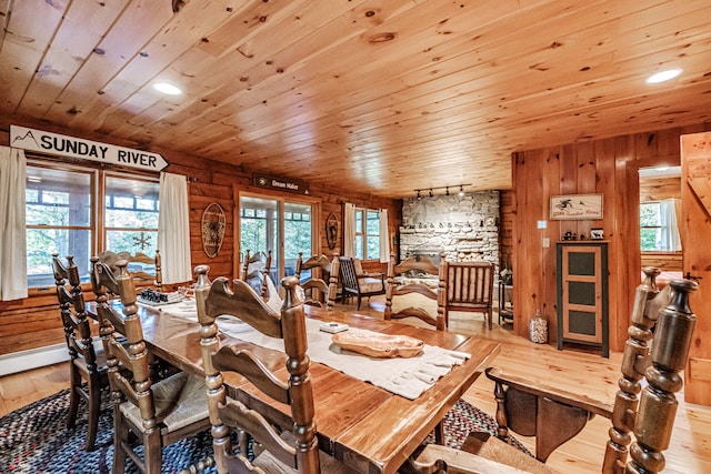 dining room featuring light wood-type flooring, wood ceiling, and wooden walls