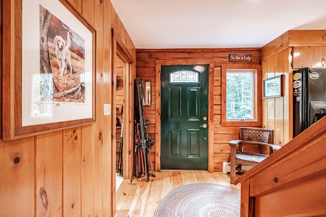 foyer entrance featuring light hardwood / wood-style floors and wooden walls