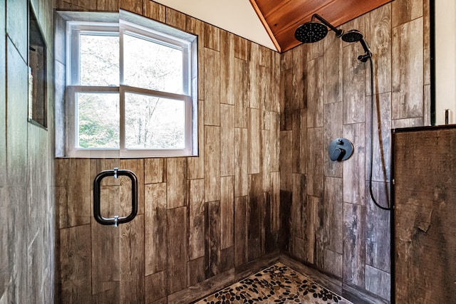 bathroom featuring walk in shower, wooden walls, plenty of natural light, and lofted ceiling