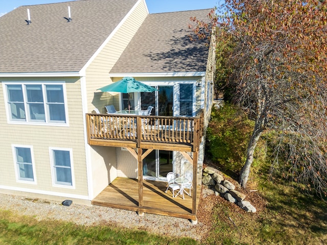 back of property with a shingled roof and a wooden deck