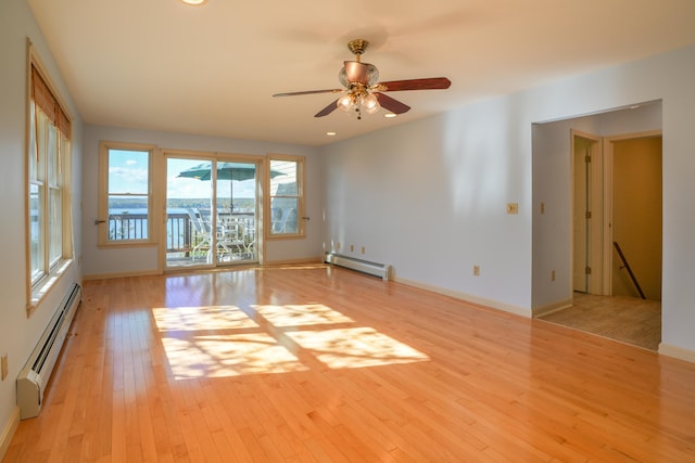 empty room with light wood finished floors, a baseboard radiator, baseboards, and a ceiling fan