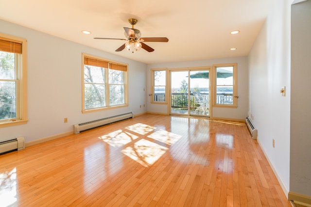 unfurnished room featuring light wood-type flooring, a healthy amount of sunlight, and a baseboard heating unit