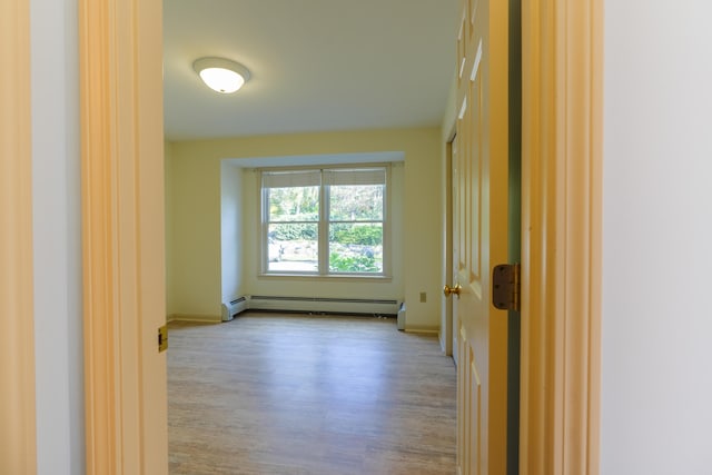 spare room with baseboards, baseboard heating, and light wood-style floors