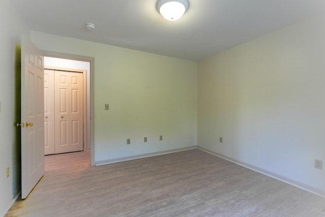 unfurnished room with light wood-type flooring and baseboards