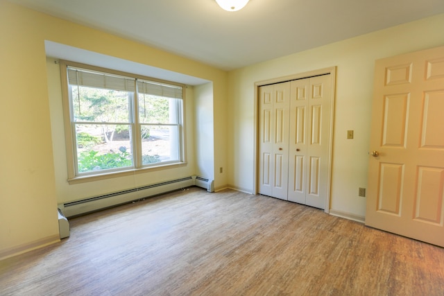 unfurnished bedroom with light wood-type flooring, a baseboard radiator, baseboards, and a closet