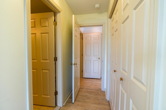 corridor featuring light wood-style flooring and baseboards