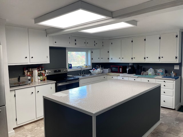 kitchen featuring white cabinets, appliances with stainless steel finishes, sink, and a kitchen island