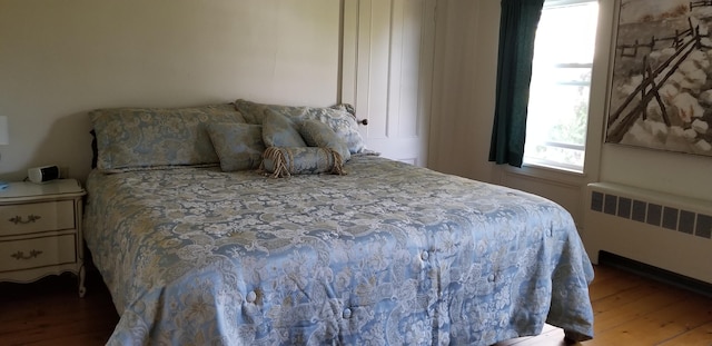 bedroom featuring radiator heating unit and hardwood / wood-style flooring