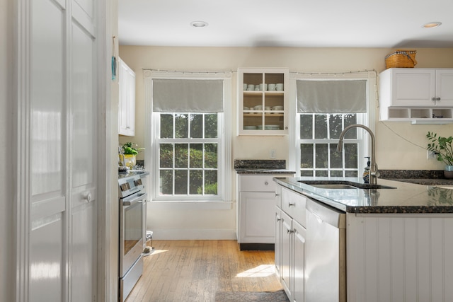 kitchen with light wood-type flooring, stainless steel range oven, sink, white cabinets, and white dishwasher