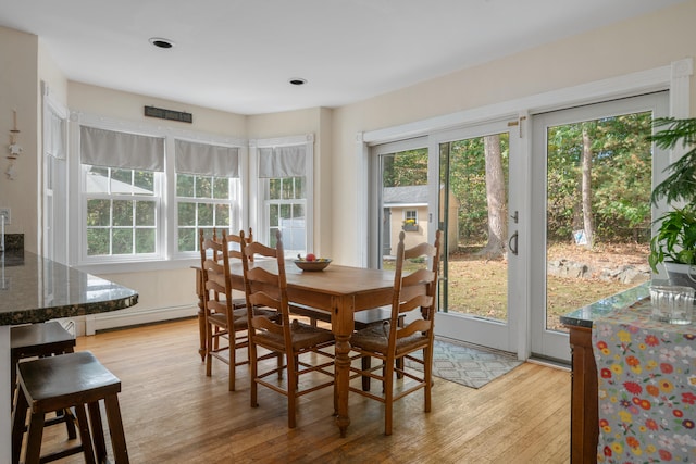 dining space featuring light hardwood / wood-style flooring, a baseboard radiator, and plenty of natural light