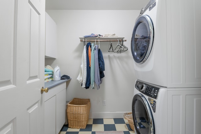 laundry area with stacked washer / dryer and cabinets