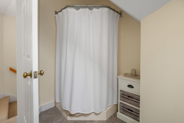 bathroom with walk in shower, lofted ceiling, and tile patterned flooring