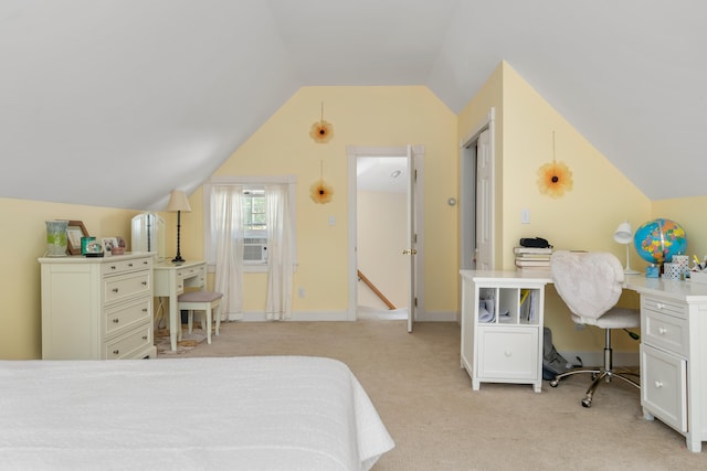 carpeted bedroom with built in desk and vaulted ceiling