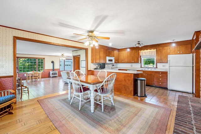 dining room with light tile patterned flooring, plenty of natural light, sink, and a wood stove