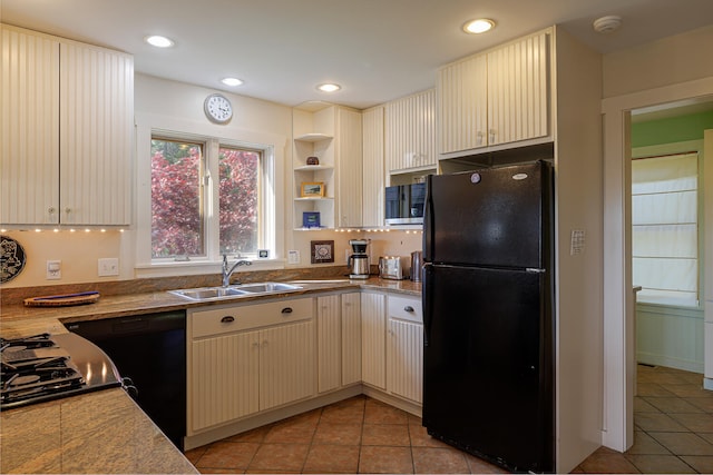 kitchen featuring light tile patterned floors, cream cabinetry, sink, and black appliances