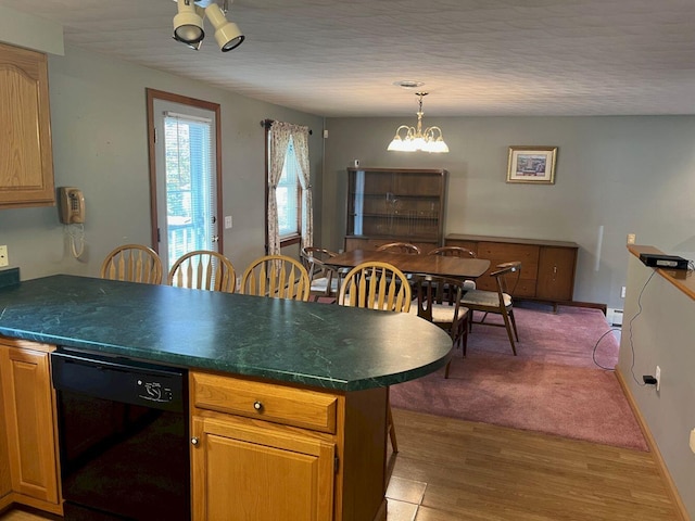 kitchen featuring dishwasher, a notable chandelier, kitchen peninsula, pendant lighting, and hardwood / wood-style flooring