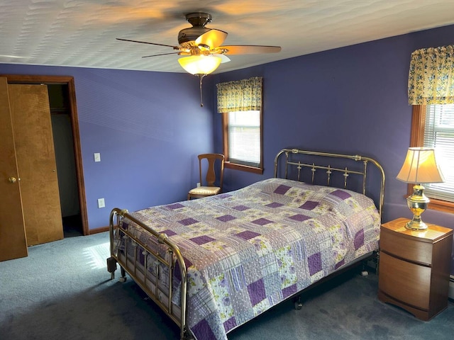 bedroom featuring ceiling fan, dark carpet, and multiple windows