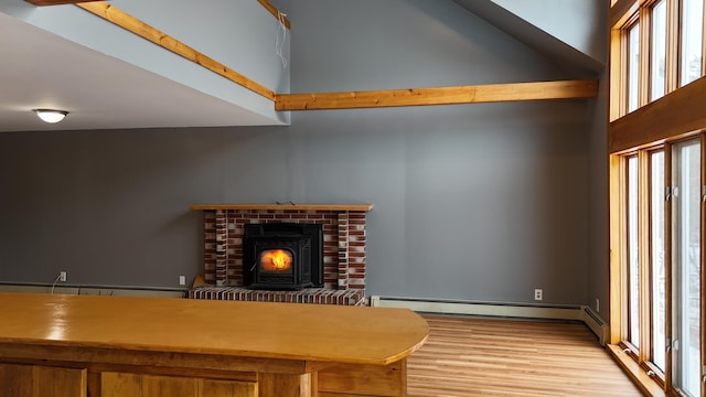 unfurnished living room with baseboard heating, light wood-type flooring, and a high ceiling