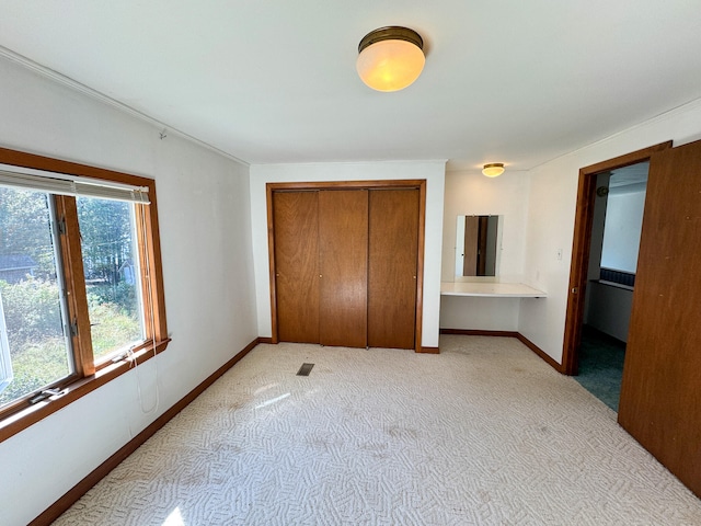 unfurnished bedroom featuring light carpet and a closet