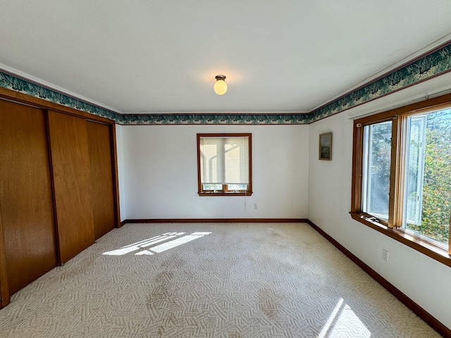 unfurnished bedroom with multiple windows, light carpet, and a closet