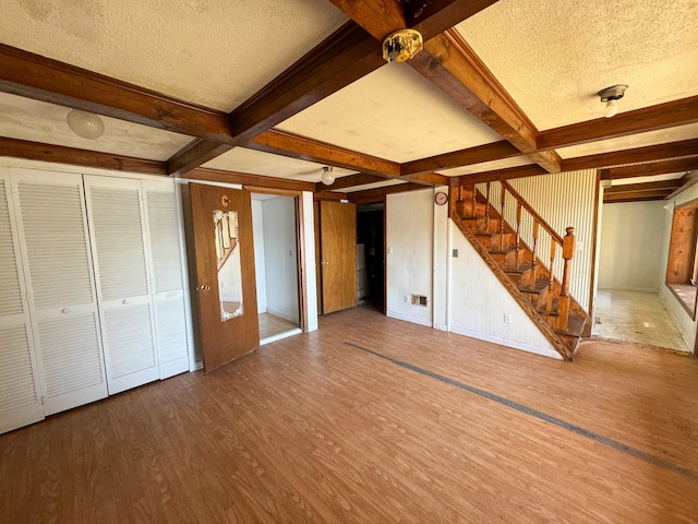 unfurnished living room with coffered ceiling, a textured ceiling, beamed ceiling, and hardwood / wood-style floors