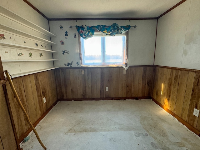 spare room featuring ornamental molding and wood walls