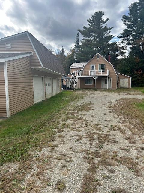 473 Wolfboro Rd, Stetson, ME 04488 - exterior space featuring a gambrel roof, a wooden deck, stairway, a garage, and dirt driveway