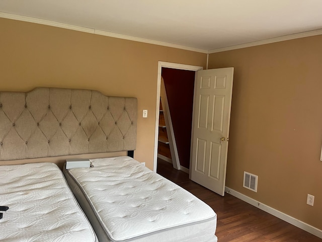 bedroom with ornamental molding and dark wood-type flooring