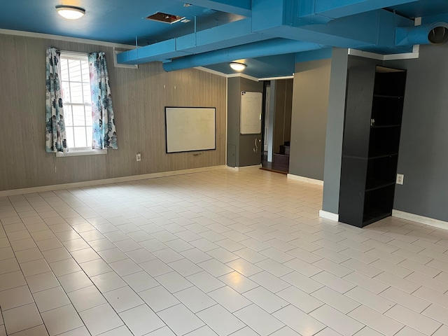 basement featuring light tile patterned flooring and wooden walls