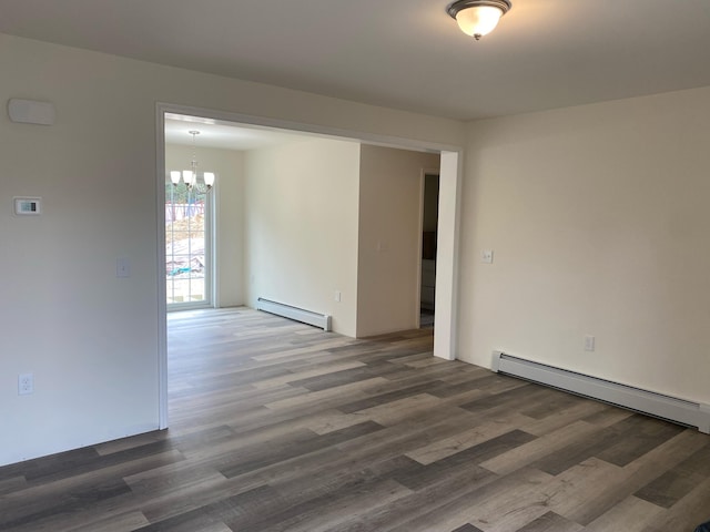 spare room featuring wood finished floors, a baseboard heating unit, and an inviting chandelier