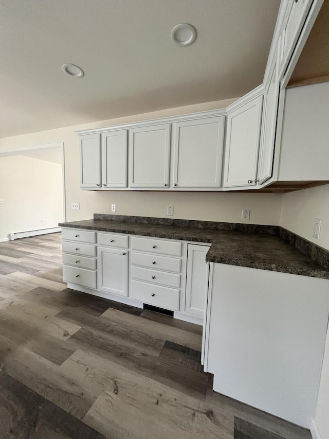 kitchen with dark wood-style flooring, recessed lighting, dark countertops, white cabinets, and a baseboard radiator