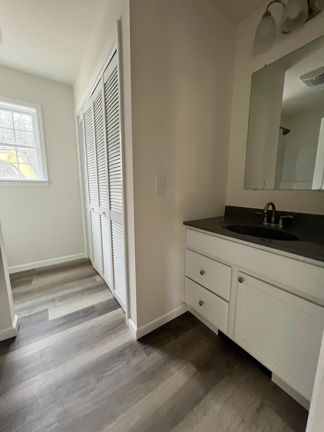 bathroom featuring vanity, baseboards, visible vents, and wood finished floors