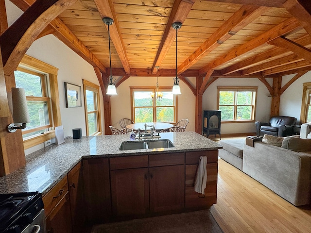 kitchen with light wood-type flooring, hanging light fixtures, dark stone countertops, and a healthy amount of sunlight