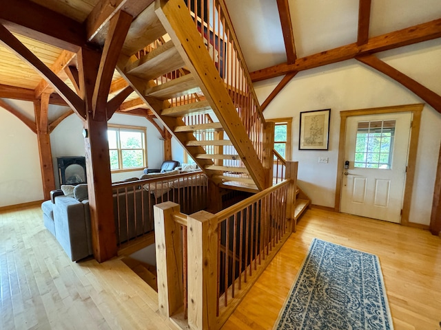 stairway with vaulted ceiling with beams and hardwood / wood-style floors