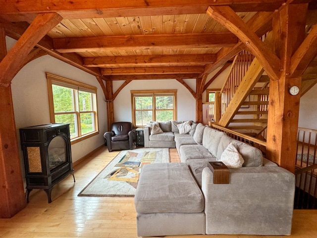 living room featuring light hardwood / wood-style flooring, beam ceiling, a wood stove, and a healthy amount of sunlight