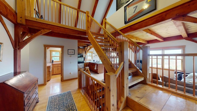 staircase with wood ceiling, vaulted ceiling with beams, hardwood / wood-style floors, and a healthy amount of sunlight