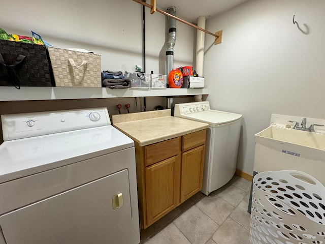 clothes washing area featuring light tile patterned floors, sink, washer and dryer, and cabinets