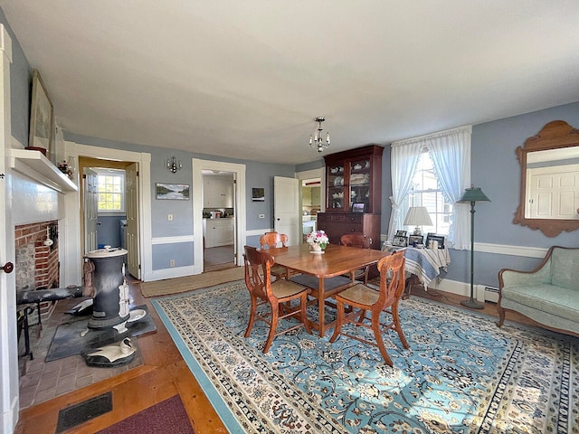 dining space featuring hardwood / wood-style floors, a baseboard heating unit, and a fireplace