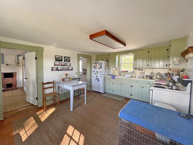 kitchen with dark colored carpet, a brick fireplace, sink, and white appliances