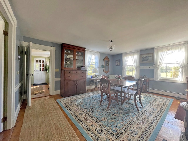 dining area featuring a notable chandelier, wood-type flooring, and a baseboard heating unit