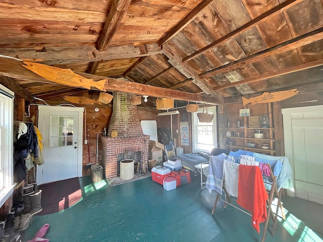 interior space with wood walls, wooden ceiling, vaulted ceiling with beams, and a fireplace