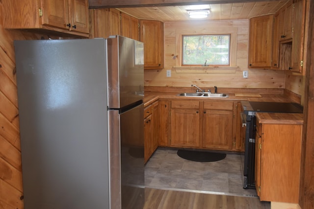 kitchen with wood walls, stainless steel fridge, and sink