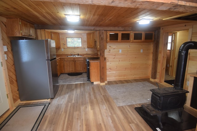 kitchen with wooden walls, stainless steel refrigerator, and light hardwood / wood-style floors